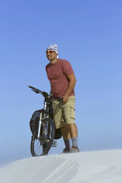 Ταξιδεύει ο άνθρωπος σε ένα ποδήλατο στην έρημο. — Φωτογραφία Αρχείου