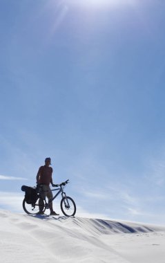 Adam çölde bir bisikletle seyahat.