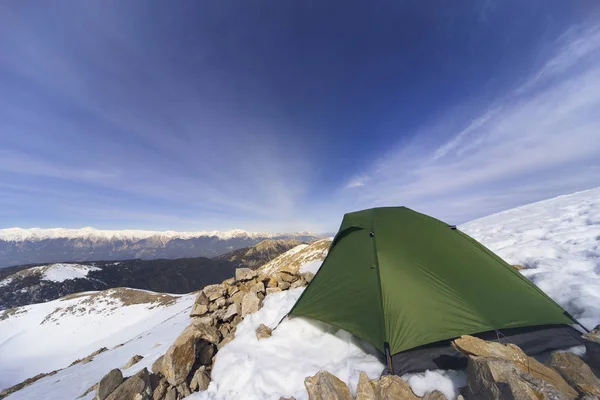 Winter camping in the mountains with a backpack and tent.