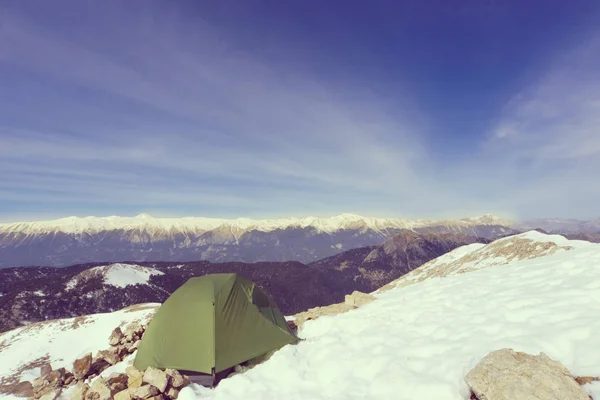 Winter camping in the mountains with a backpack and tent.