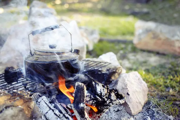 Make tea over an open fire in a hike. — Stock Photo, Image
