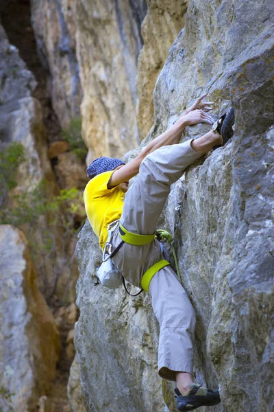 Jeune grimpeur masculin accroché à une falaise avec une corde . — Photo