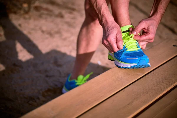 Atleta durante el entrenamiento atando cordones en zapatillas de verano . — Foto de Stock