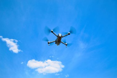 Mavi gökyüzü karşı bir gri quadrocopter uçuş.