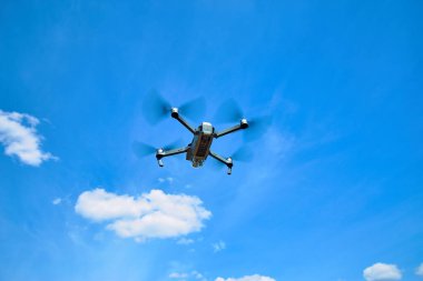 Mavi gökyüzü karşı bir gri quadrocopter uçuş.