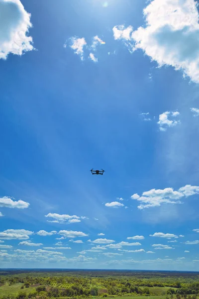 Voo de um quadrocopter cinza contra um céu azul . — Fotografia de Stock