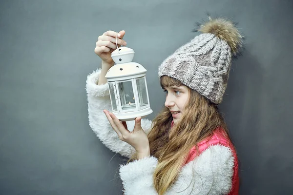 Girl with a white lamp in hands on a gray background.