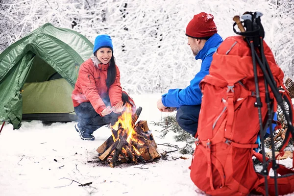 Winter camping in the forest with a tent and a fire.