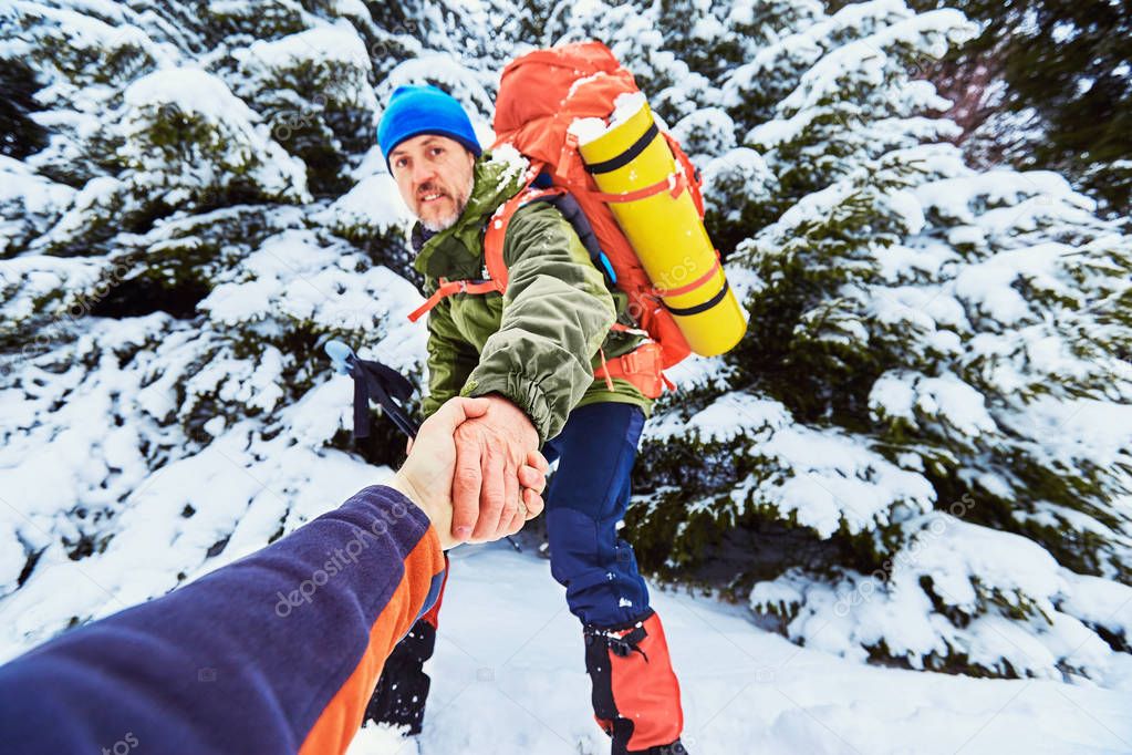 A helping hand high up in the mountains in the winter hike.
