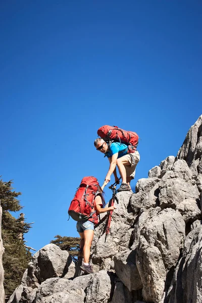 在远足中为一个女孩的高山伸出援助之手. — 图库照片