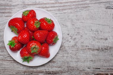 Eski ahşap zemin üzerine kase çilek yığını. Üstten Görünüm.