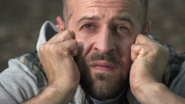 kel adam sinirli ve umutsuz yumruklarını yüzünde clenches