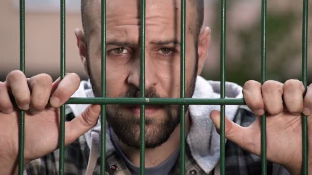 Trauriger und frustrierter Mann hinter Gittern — Stockvideo