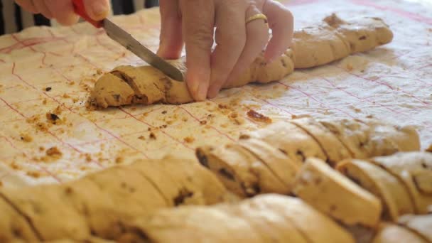 Mani di donna tagliano con cura i tozzetti, tipici biscotti italiani — Video Stock