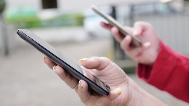 Dos manos de mujer charlando intensamente con teléfonos inteligentes en la calle — Vídeos de Stock