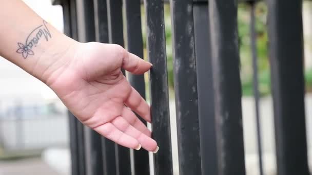 Vrouw hand zachtjes aanraken de ijzeren staven van een gebouw — Stockvideo