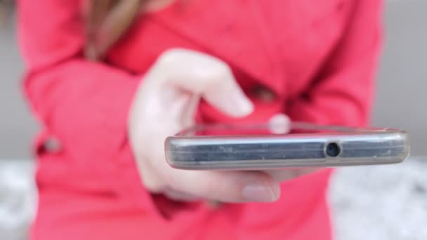 Mujer con abrigo rojo escribe mensajes en el teléfono inteligente — Vídeo de stock