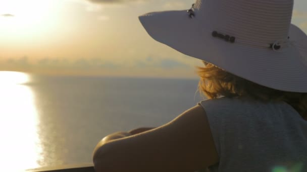 Mujer sofisticada con sombrero blanco contempla la puesta de sol — Vídeo de stock