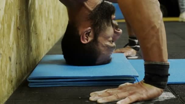 Handsome athlete trains with the handstand at the gym — ストック動画