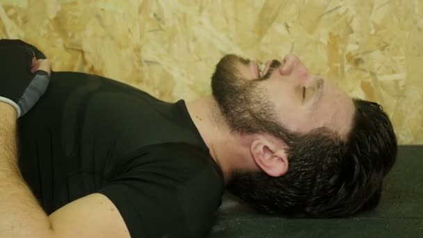 Досвідчений спортсмен вдихає, лежачи на землі — стокове відео