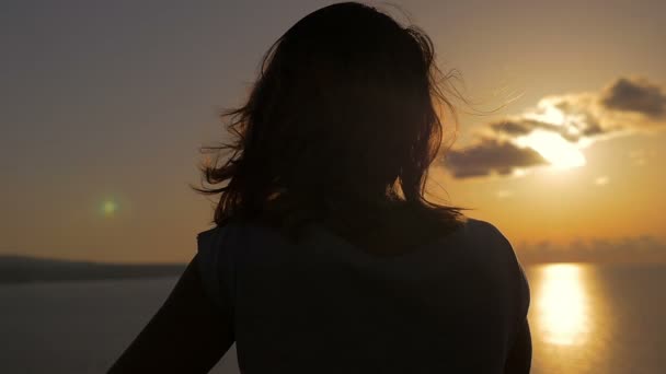 Споглядальна жінка назад спостерігає за морем під час заходу сонця — стокове відео