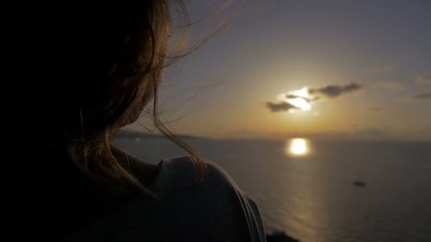 Vrouw kijkt naar de zee, terwijl de wind ruffles haar haren — Stockvideo