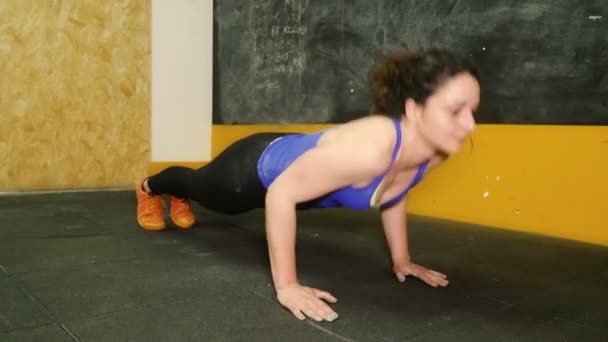 Woman who practices crossfit does pushups on the floor — ストック動画