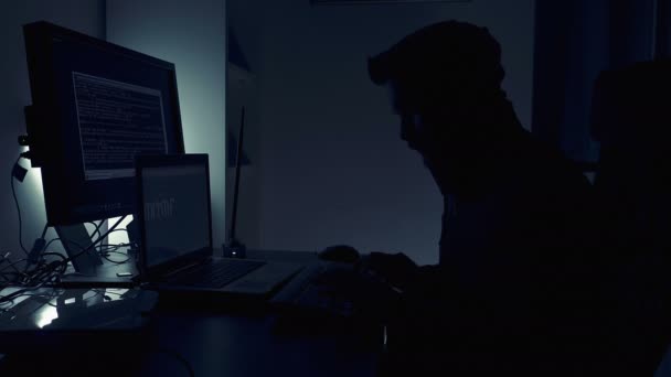 Hacker silouhette in the dark while typing on his computer — Stock Video