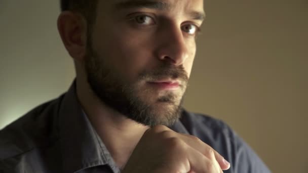 Profile of guy with beard reflecting, resting his face on his hand — ストック動画
