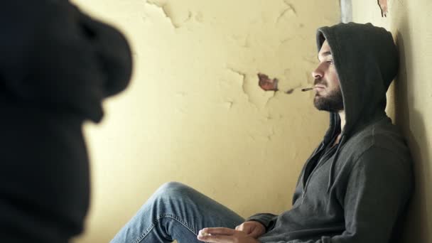 Наркоторговец на ступеньках заброшенного здания продает наркотики — стоковое видео