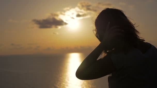 Silueta mladé ženy dotýká jejích vlasů při sledování slunce — Stock video