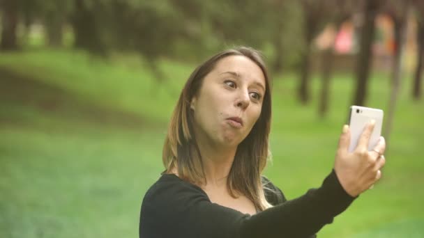 Mujer feliz en un parque mientras hace una autofoto divertida — Vídeo de stock
