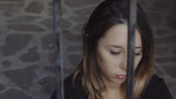 Traurige und nachdenkliche Frau hinter Gittern — Stockvideo
