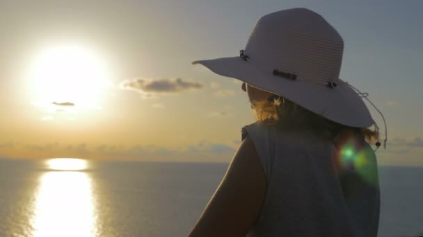 Κομψή γυναίκα με καπέλο ενώ παρατηρείτε το ηλιοβασίλεμα — Αρχείο Βίντεο