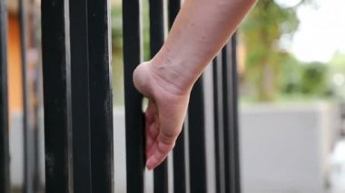  kadın eli yavaşça dokun bir binanın Demir parmaklıkları