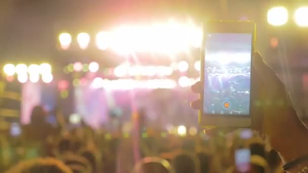 De hand van de man is het opnemen van het rock concert in de menigte met zijn smartphone — Stockvideo