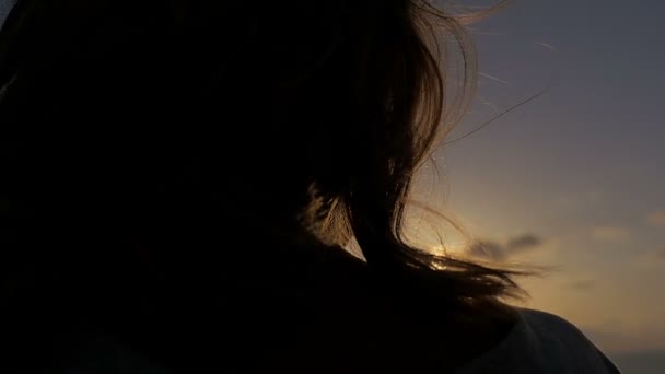 Vrouw terug in backlit overweegt de zonsondergang — Stockvideo