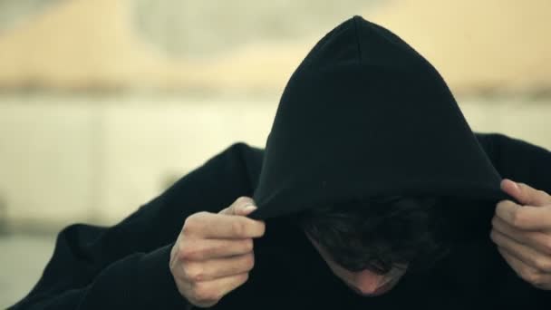 Aggressive hacker he is wearing the hood and looks menacingly at camera — Stockvideo