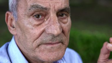 yaşlı adam meydan okurcasına bir sigara kameraya benziyor