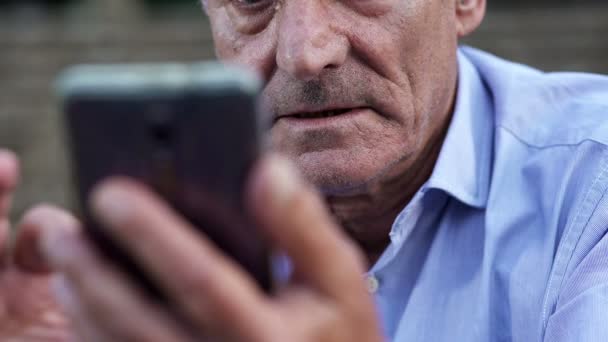 Elderly man intent on using  mobile phone — Stock video