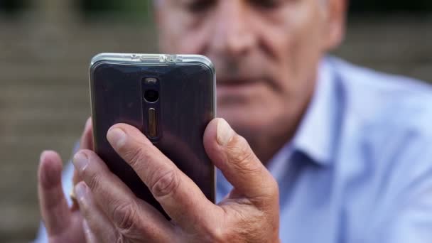 Homem idoso digitando no telefone móvel com cuidado — Vídeo de Stock