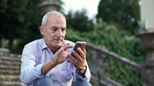 Gepensioneerde man alleen naar het park te typen op mobiel — Stockvideo