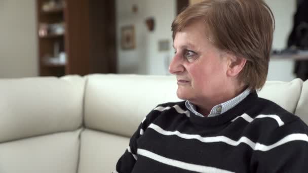 Happy elderly woman on the couch smiling at the camera — Stock video