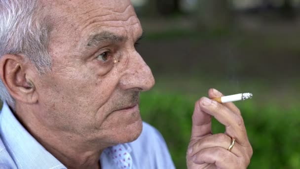 Un hombre mayor pensativo fuma un cigarrillo — Vídeos de Stock