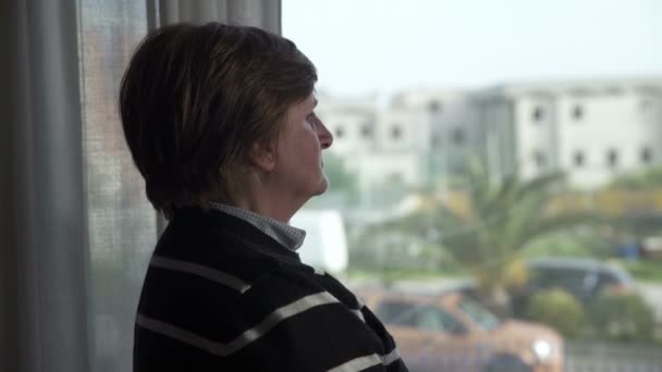 Elderly woman at the window waiting for her husband — Stock video