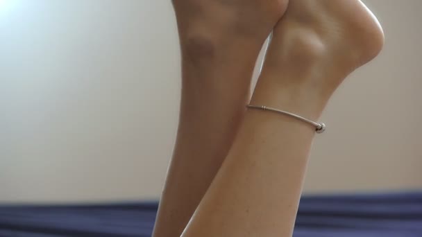 Молодая женщина скрестила ноги, двигаясь на кровати — стоковое видео