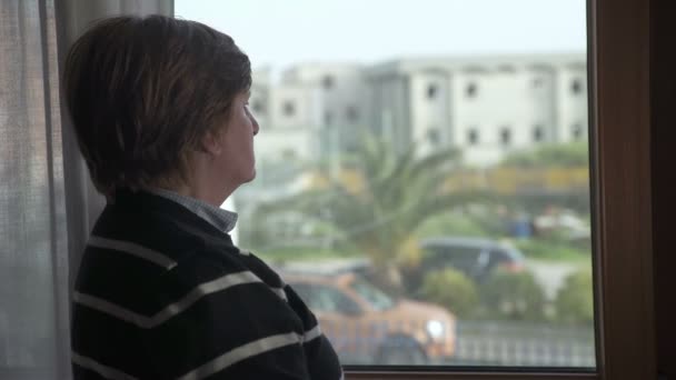 Pensive mature woman at the window — Αρχείο Βίντεο