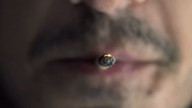 adam ağız detay sigara ve bir sigara yakıyor