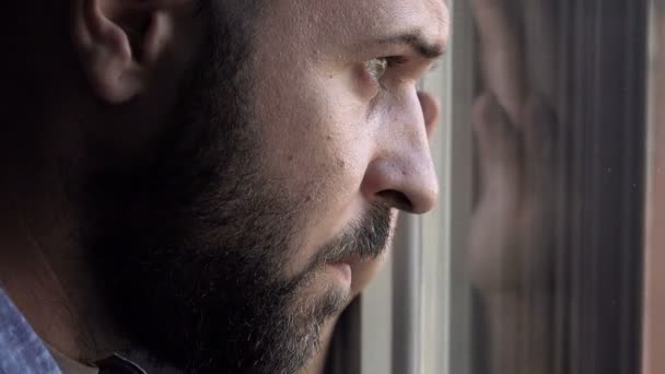 Homem sério encostado à janela olhando para fora — Vídeo de Stock