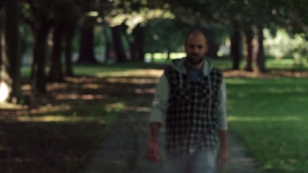 Homem careca andando no parque na câmera, parar cruza os braços e sorri — Vídeo de Stock